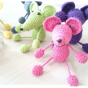 Peut inclure: Cinq souris en crochet de différentes couleurs : jaune, gris, vert, rose et violet. Les souris sont assises sur une surface en bois clair.