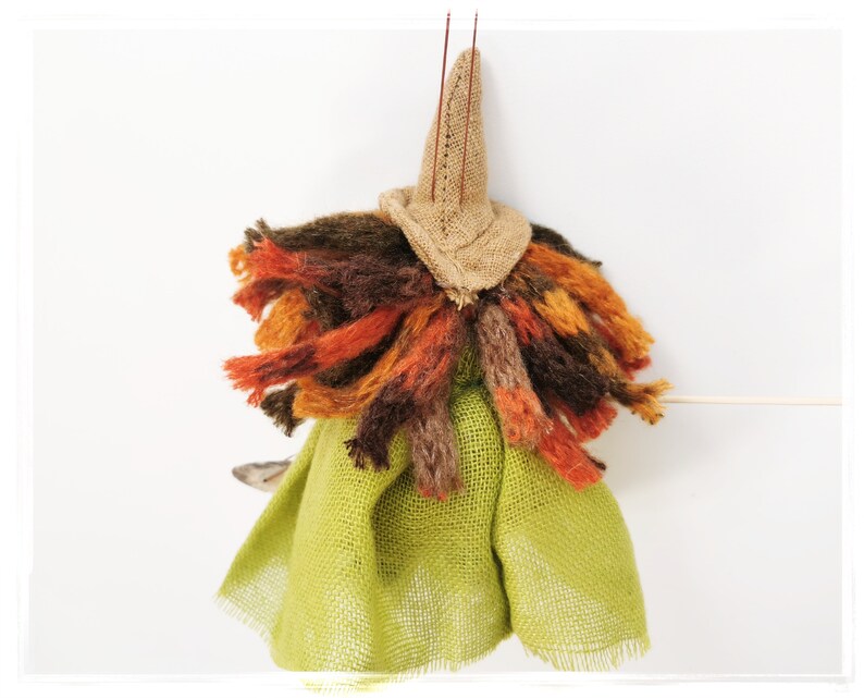May include: A handmade witch doll with a brown burlap hat, a green burlap skirt, and a long, colorful yarn hair.