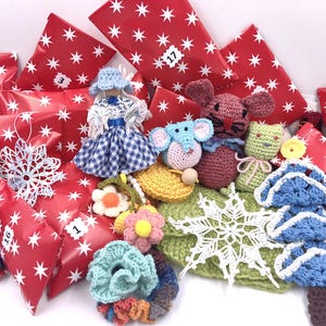 Peut inclure: Une collection d'articles faits à la main, dont une poupée, des animaux crochetés, des fleurs et des flocons de neige, disposés avec des boîtes cadeaux rouges ornées d'étoiles blanches et de numéros. Les articles sont de couleurs variées.