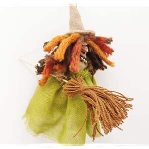May include: A handmade witch doll with a brown, orange, and yellow yarn wig, a green burlap skirt, and a brown yarn broom.