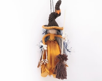 May include: A handmade witch doll with long gray yarn hair, wearing a brown crocheted hat with a black spider, a gold dress, and holding a broom.