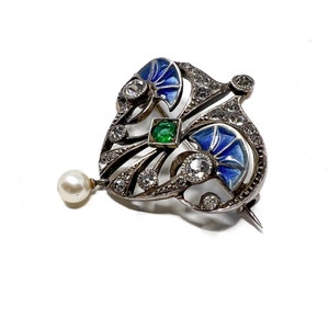 K&ouml;nnte beinhalten: Eine silberne Brosche mit blauem und gr&uuml;nem Email, besetzt mit Diamanten und einem Perlenanh&auml;nger.