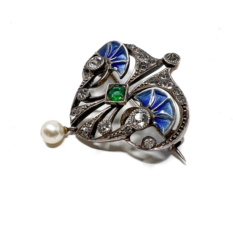 K&ouml;nnte beinhalten: Eine silberne Brosche mit blauem und gr&uuml;nem Email, besetzt mit Diamanten und einem Perlenanh&auml;nger.