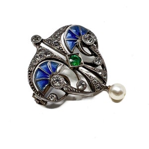 K&ouml;nnte beinhalten: Eine silberne Brosche mit blauem und gr&uuml;nem Email, besetzt mit Diamanten und einem Perlenanh&auml;nger.