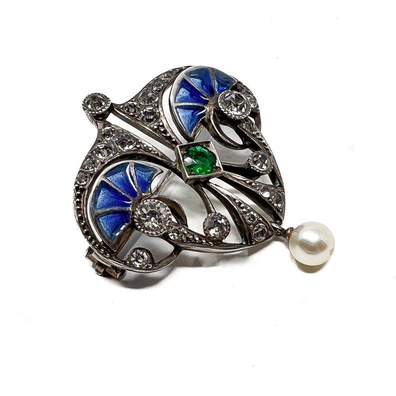 K&ouml;nnte beinhalten: Eine silberne Brosche mit blauem und gr&uuml;nem Email, besetzt mit Diamanten und einem Perlenanh&auml;nger.