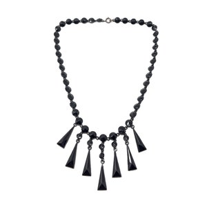 May include: A black necklace with a row of round beads and a dangling fringe of triangular beads.
