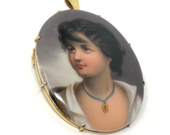 May include: A gold oval locket with a painted portrait of a woman with dark hair and a blue necklace. The locket has a detailed gold frame.