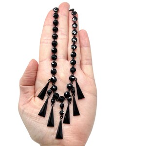 May include: A black jet necklace with a long chain and multiple dangling triangular pendants.