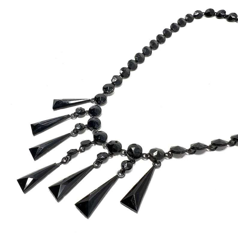 May include: A black jet necklace with a dangling row of black teardrop-shaped beads.