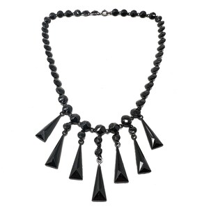 May include: A black glass necklace with a long chain and a dangling pendant of five black glass teardrop shapes.