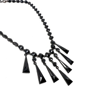 May include: A black beaded necklace with a dangling fringe of black faceted teardrop-shaped beads.