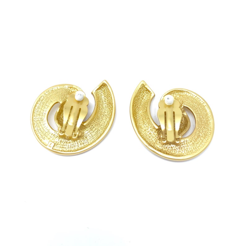 May include: A pair of gold tone clip-on earrings with a swirl design and a faux pearl accent.