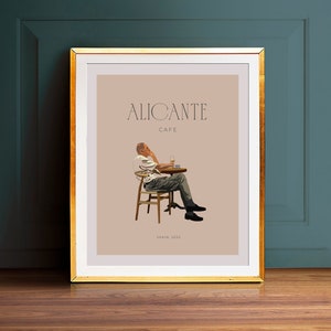 Può includere: Un poster beige con il testo "ALICANTE CAFE" in nero. Un uomo è seduto a un tavolo con un bicchiere di vino e una tazza di caffè. Il poster ha il testo "SPAIN, 2022" in basso.