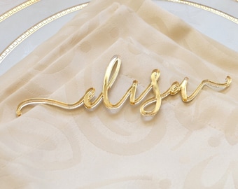 May include: Gold acrylic place card with the name "Alison" written in cursive.