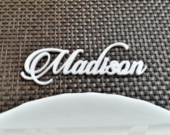 Peut inclure: Carte de nom en plastique blanc avec le nom "Madison" écrit en cursive.