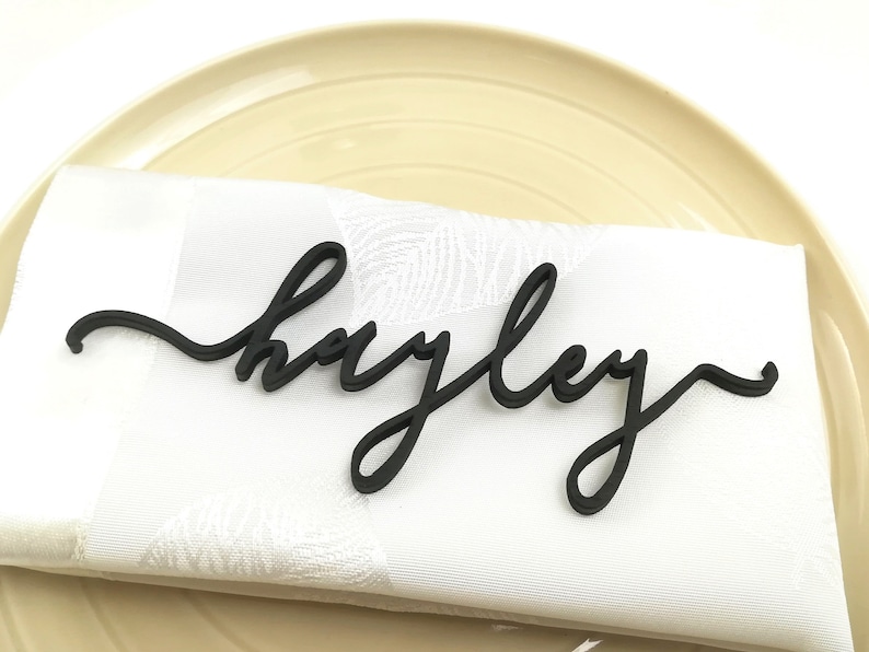 May include: Black wooden name card with the name "Hayley" written in a cursive font.