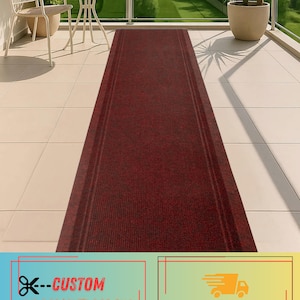 May include: A burgundy indoor/outdoor rug runner with a textured surface. The rug has a rectangular shape and is placed on a tiled surface. The text "CUSTOM INDOOR/OUTDOOR RUG RUNNER" is visible at the bottom of the image.