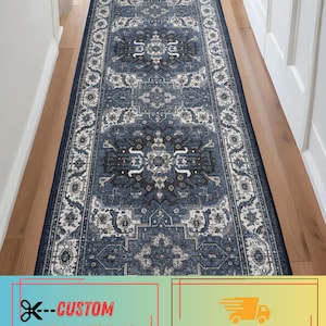 May include: A long rectangular runner rug featuring a deep blue, charcoal, and cream color palette. The rug displays a repeating intricate medallion pattern with ornate floral motifs and a decorative border, laid out in a narrow hallway.