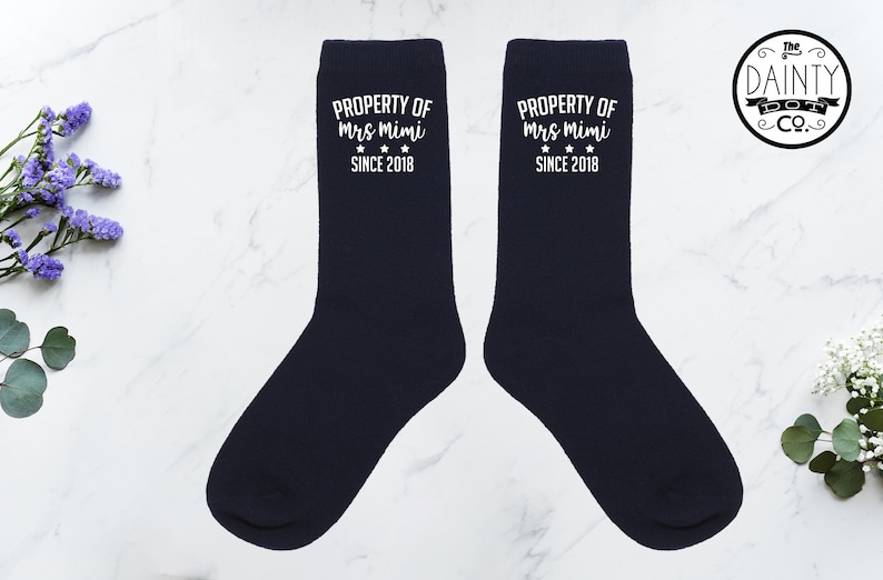 May include: Pair of navy blue socks with white text that reads "PROPERTY OF Mrs Mimi SINCE 2018".
