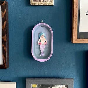 Könnte beinhalten: Ein Set aus drei Keramikbechern mit gesprenkelter, matter Oberfläche. Die Becher sind in Creme-, Hellgrau- und Dunkelgrautönen gehalten. Jeder Becher hat ein schlichtes, modernes Design und einen abgerundeten Griff.