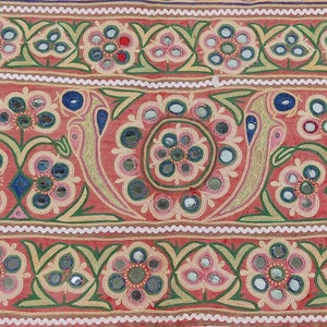 Puede incluir: Un panel de tela rojo con un patr&oacute;n repetido de flores bordadas y peque&ntilde;os espejos. Las flores son en tonos de rosa, verde y azul. Los espejos son redondos y tienen un acabado plateado.