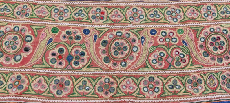 Puede incluir: Un panel de tela rojo con un patr&oacute;n repetido de flores bordadas y peque&ntilde;os espejos. Las flores son en tonos de rosa, verde y azul. Los espejos son redondos y tienen un acabado plateado.