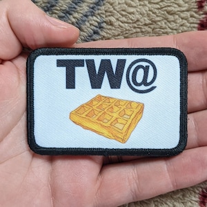 May include: A black and white patch with the text "TW@" and a cartoon image of a waffle.