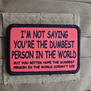 May include: A rectangular patch with the text "I'M NOT SAYING YOU'RE THE DUMBEST PERSON IN THE WORLD BUT YOU BETTER HOPE THE DUMBEST PERSON IN THE WORLD DOESN'T DIE" in black on a red background, with a black border.