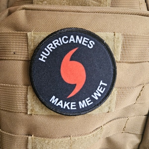 May include: A black and red patch with the text "HURRICANES MAKE ME WET" and a red hurricane symbol.