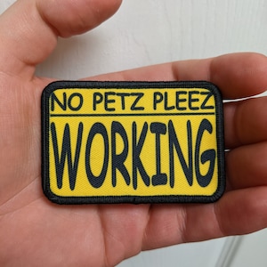 May include: Yellow and black embroidered patch with the text "NO PETZ PLEEZE WORKING" in black.
