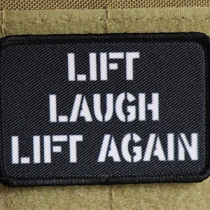 May include: Black patch with white text that reads "Lift Laugh Lift Again".