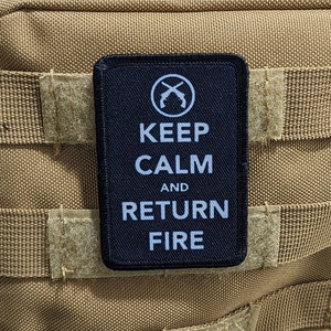 May include: Black tactical patch with white text that reads "Keep Calm and Return Fire". The patch has a crossed pistols symbol in a circle at the top.