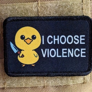 May include: A rectangular patch with a black border and background. A yellow cartoon chick holding a knife is on the patch. The text "I CHOOSE VIOLENCE" is printed in white.