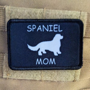 Może przedstawiać: Czarno-biała łatka z białą sylwetką psa rasy spaniel i tekstem "SPANIEL MOM" w kolorze białym.