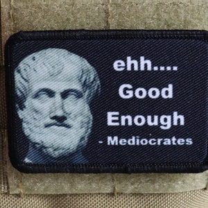 Könnte beinhalten: Schwarz-weißes Patch mit einer Büste eines Mannes und dem Text "ehh... Good Enough - Mediocrates".