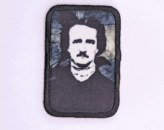 May include: Black and white embroidered patch featuring a portrait of Edgar Allan Poe. The patch has a black border and a blue and white background.