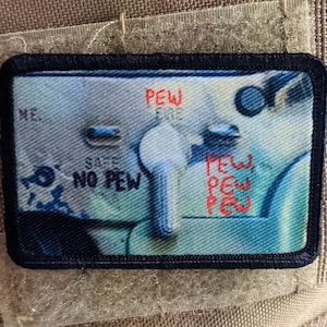 Puede incluir: Un parche negro y azul con fondo blanco. El parche presenta un primer plano de una palanca con las palabras "NO PEW" y "PEW" escritas en él.
