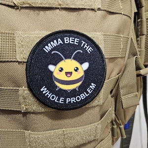 May include: A black and yellow bee patch with the text "Imma bee the whole problem" on a black background. The patch is attached to a brown tactical backpack.