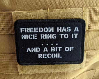 Puede incluir: Un parche negro con texto blanco que dice "Freedom has a nice ring to it... and a bit of recoil."