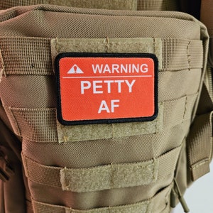 May include: A brown tactical backpack with a red and black patch that says "WARNING PETTY AF".