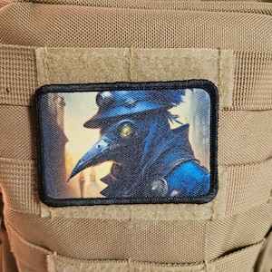 May include: A black and blue embroidered patch featuring a plague doctor wearing a long black coat, a beak mask, and a hat. The background is a blurry image of a city street.