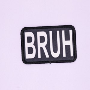 以下が含まれることがあります： 「BRUH」と白文字で書かれた黒いパッチ