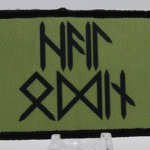 May include: A green fabric patch with black embroidered text that reads "NAIR ZODH".