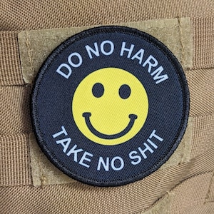 May include: Black and white patch with a yellow smiley face and the text "Do No Harm Take No Shit".