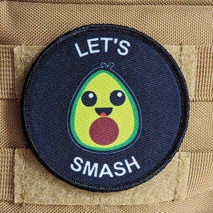 Op de afbeelding: Een zwart-witte patch met een groene avocado met een glimlachend gezicht en de tekst "Let's Smash" op een bruine achtergrond.