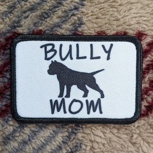 May include: White patch with black border, featuring a black silhouette of a pit bull dog and the text "BULLY MOM".