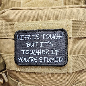 La vida es dura, pero es más dura si eres estúpido. Parche de moral divertido de 2" x 3" con fondo negro y respaldo de velcro.