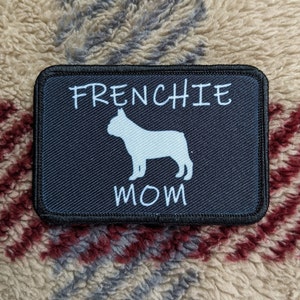 Peut inclure: Patch noir avec du texte blanc qui dit "Frenchie Mom" et une silhouette blanche d'un bouledogue français.