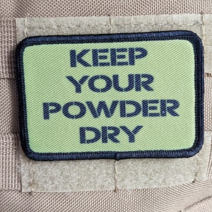 May include: A green patch with black stitching and the text "KEEP YOUR POWDER DRY" in black lettering.