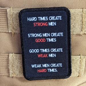 May include: A black rectangular patch with white text and red accents. The patch reads "HARD TIMES CREATE STRONG MEN, STRONG MEN CREATE GOOD TIMES, GOOD TIMES CREATE WEAK MEN, WEAK MEN CREATE HARD TIMES."